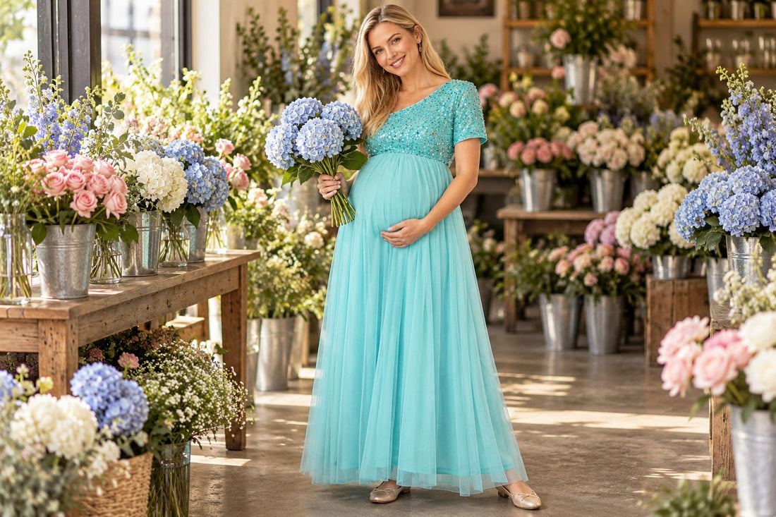 Mom-to-be in an aqua tulle maternity dress holding pale blue hydrangeas in a florist shop