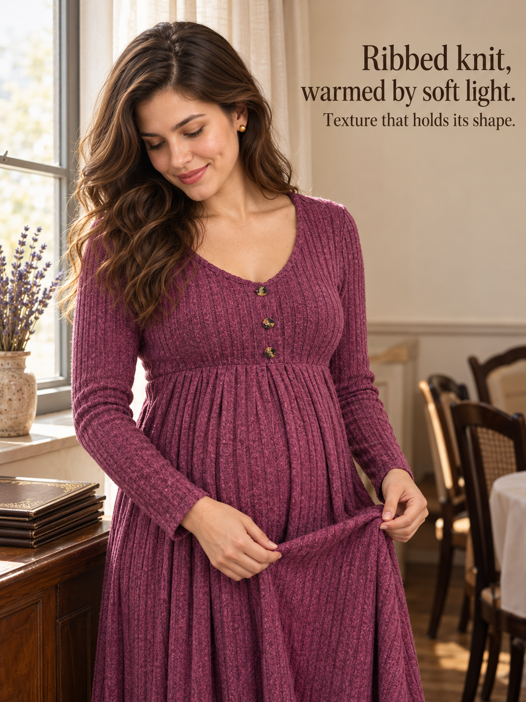 Matilda Wine Red maternity dress — standing indoors, holding out the ribbed skirt