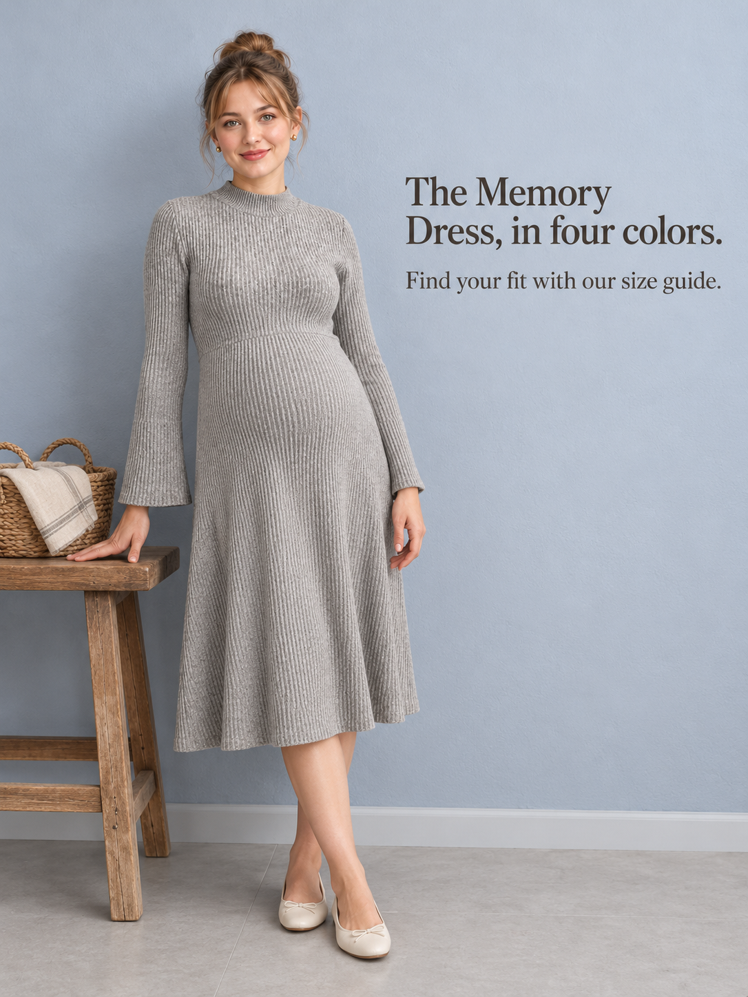 Simone Oatmeal Heather maternity dress — standing by a wall beside a rattan chair