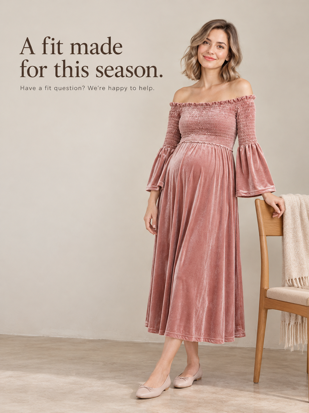 Talia Dusty Rose maternity dress — standing beside a wooden chair in soft studio light