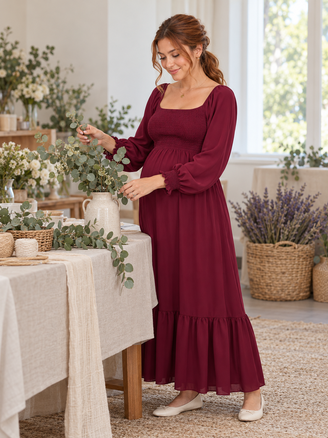 Cecily Wine Red maternity dress — arranging flowers at a table by a sunlit window