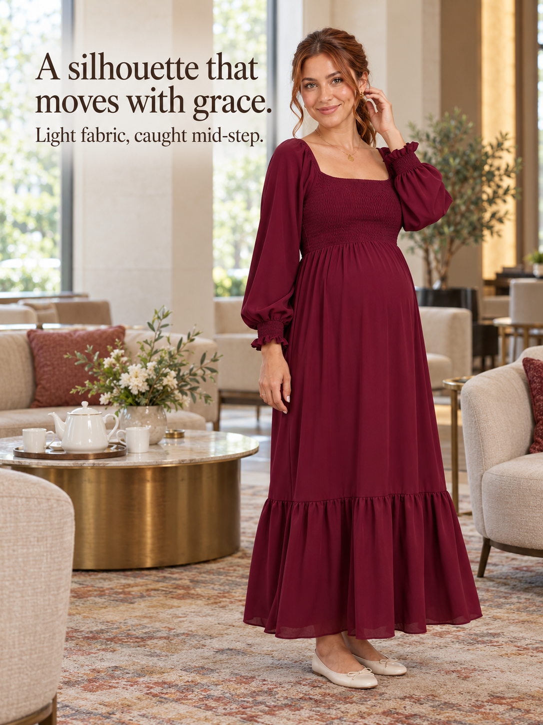 Cecily Wine Red maternity dress — walking through a plant-filled indoor seating area