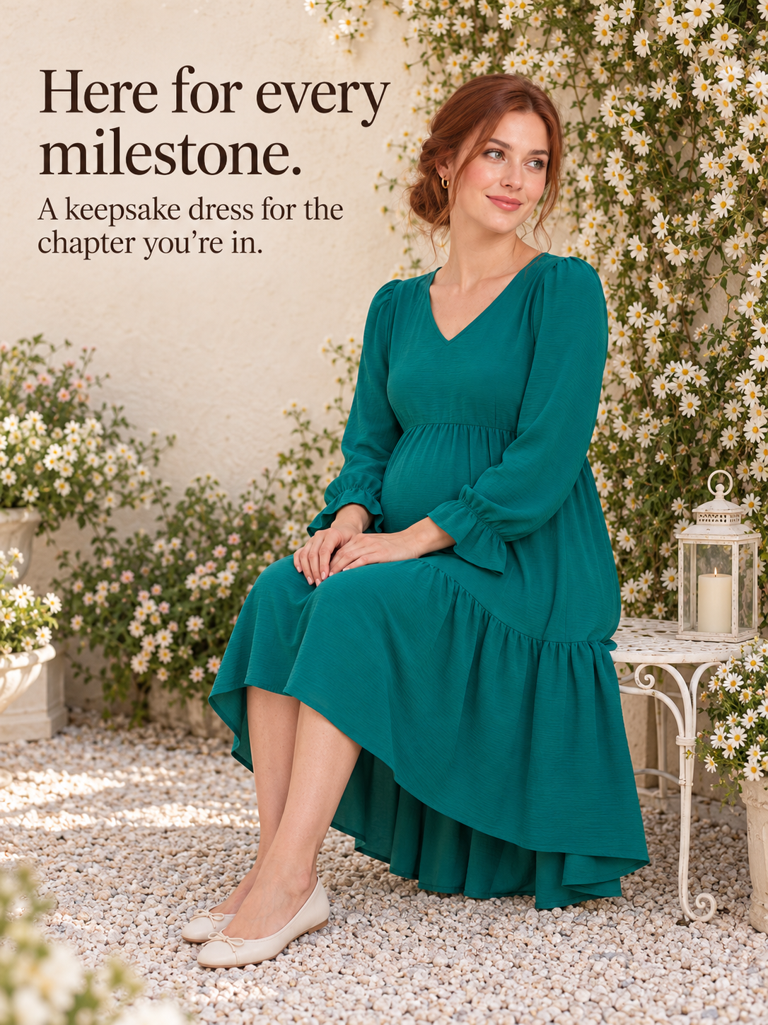Mila Emerald maternity dress — seated on a bench surrounded by white flowers