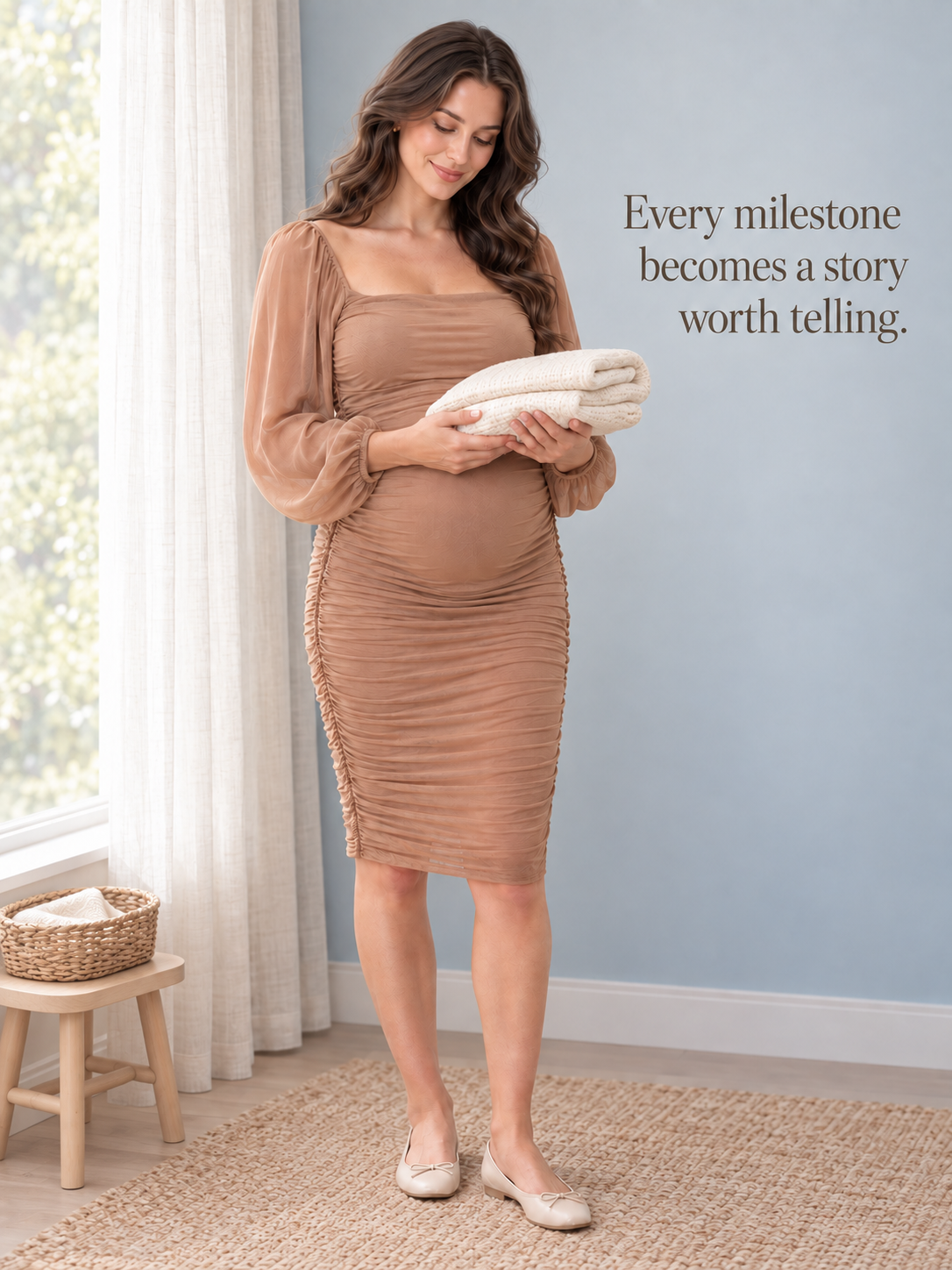 Hazel Camel maternity dress — holding a folded baby blanket by the window