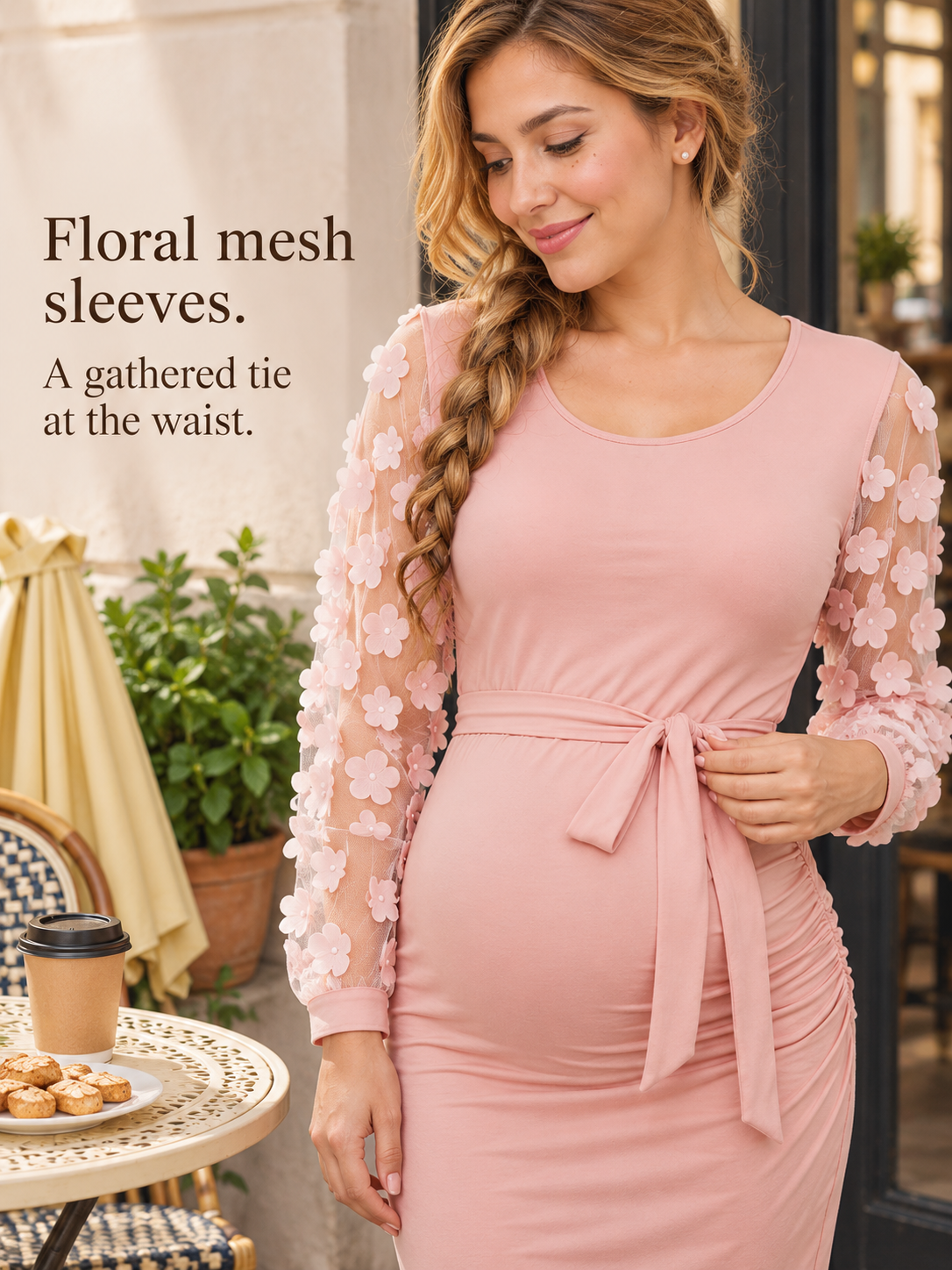 Beatrix Blush Pink maternity dress — standing indoors near plants, touching the sash bow