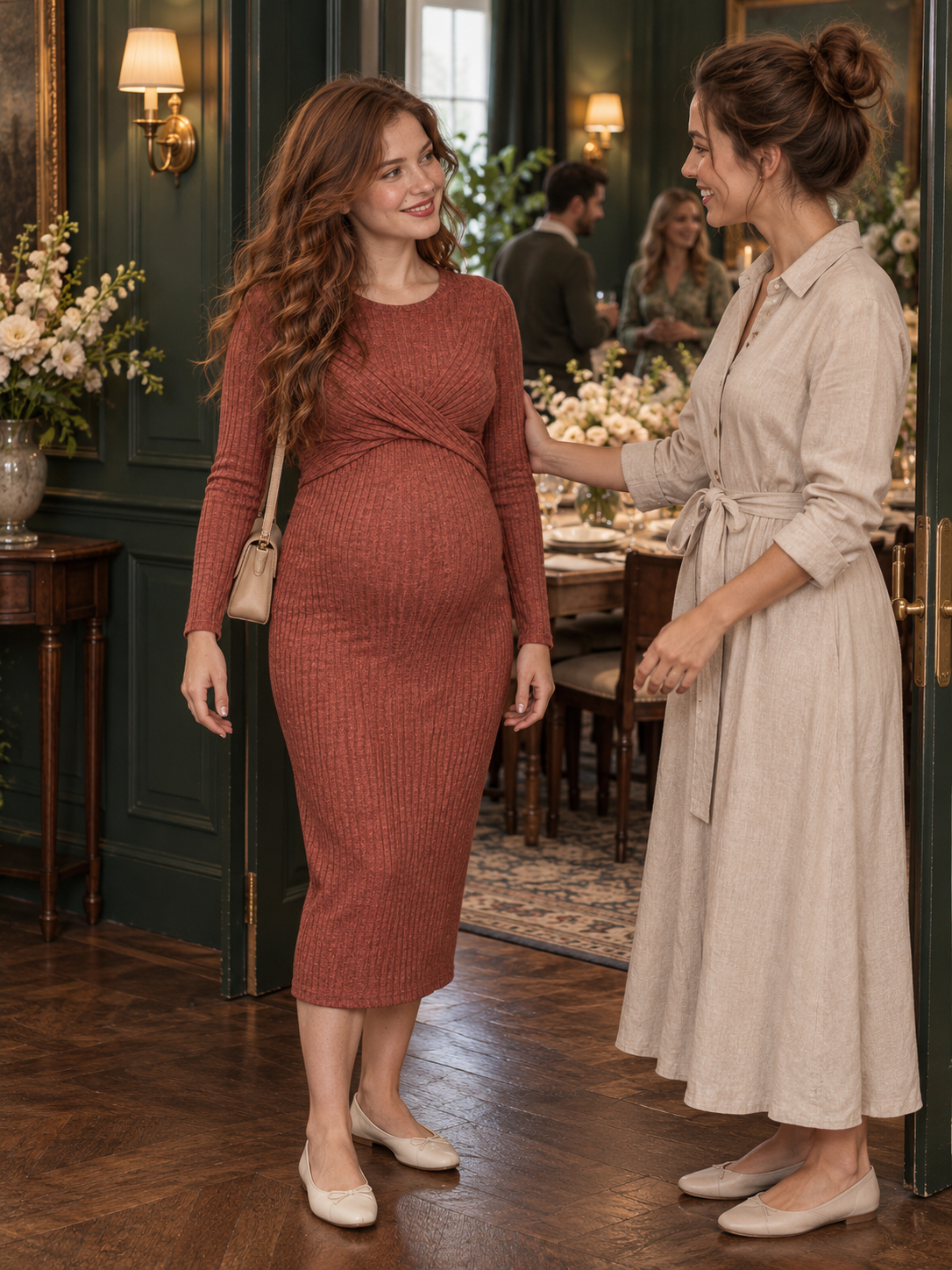 Maeve Rust Red maternity dress — greeting a guest inside a warmly lit venue