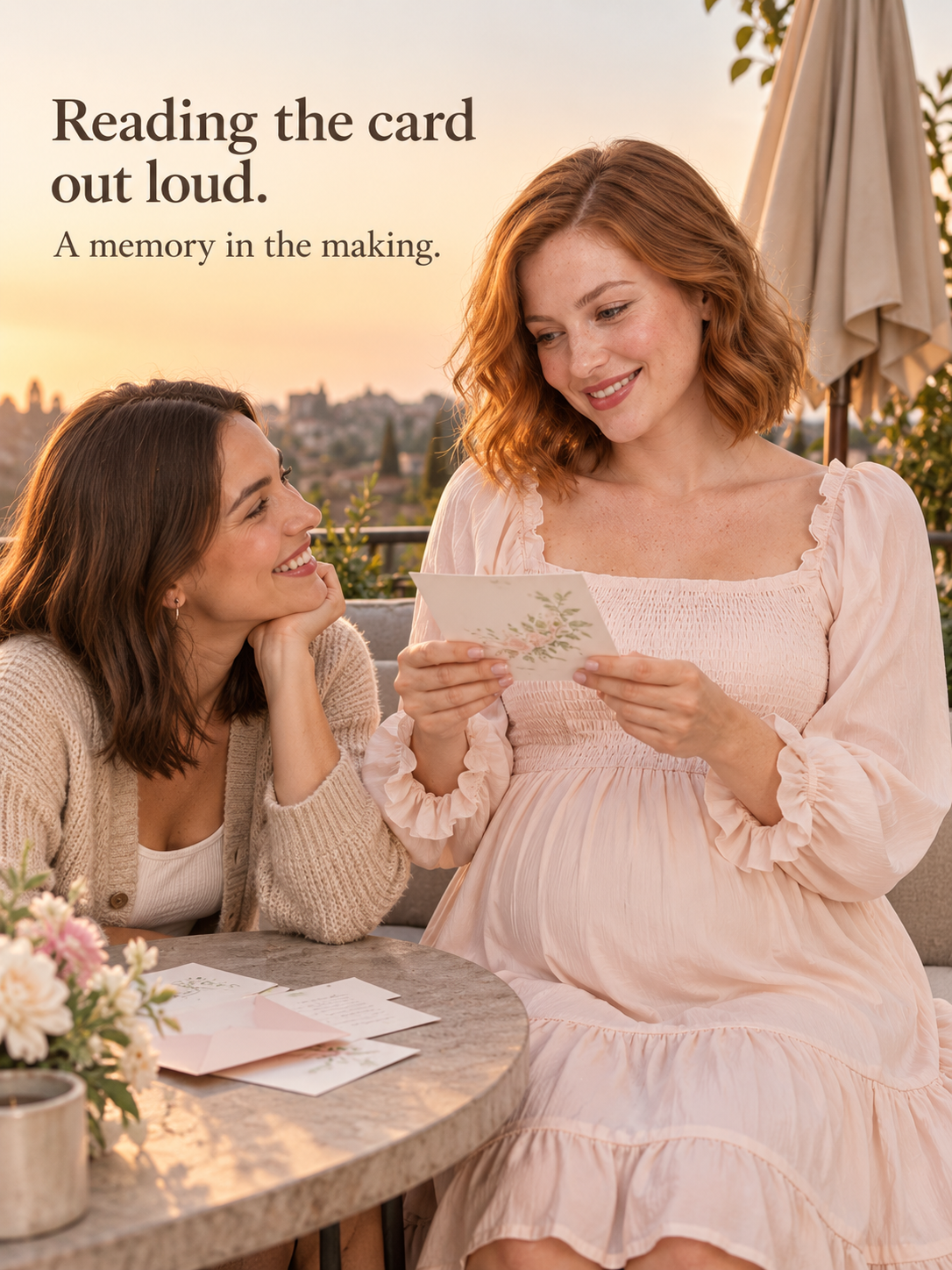 Penelope Pale Blush maternity dress — seated at an outdoor table at sunset reading a card