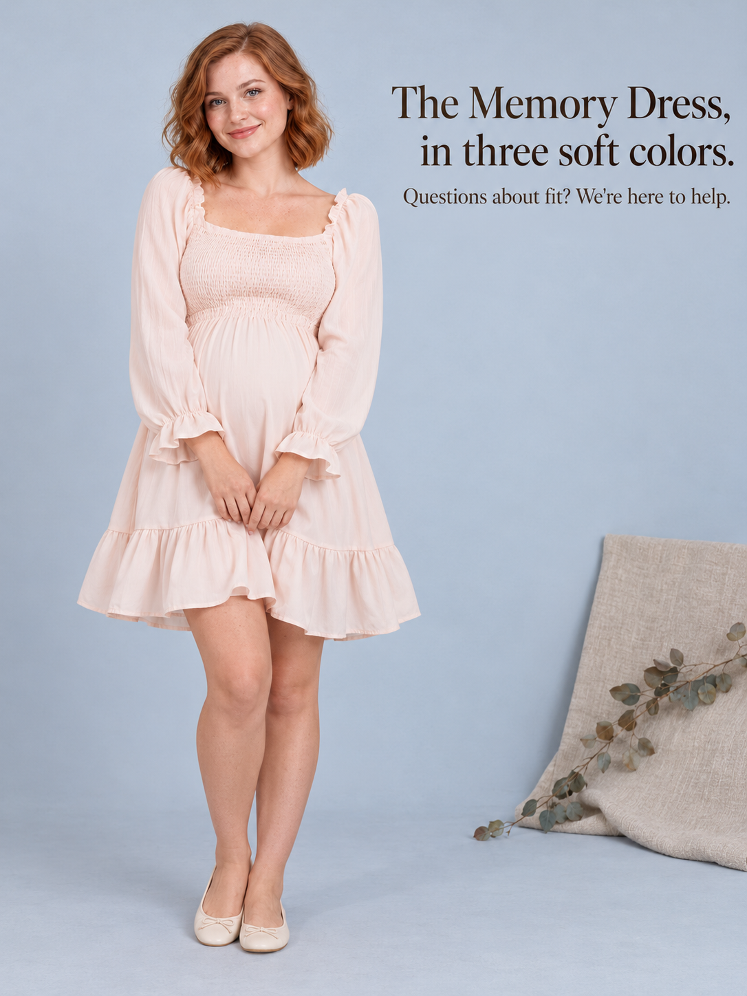 Penelope Pale Blush maternity dress — standing against a plain wall beside a folded blanket