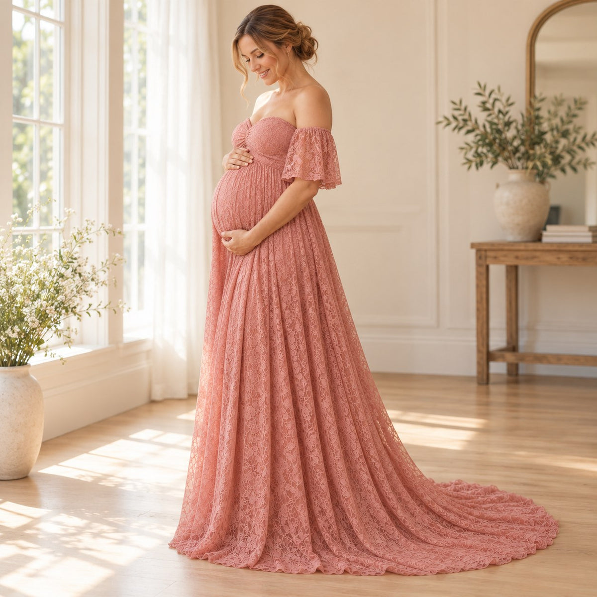 Side view of the blush pink lace maternity dress with an empire seam and a long trailing hem