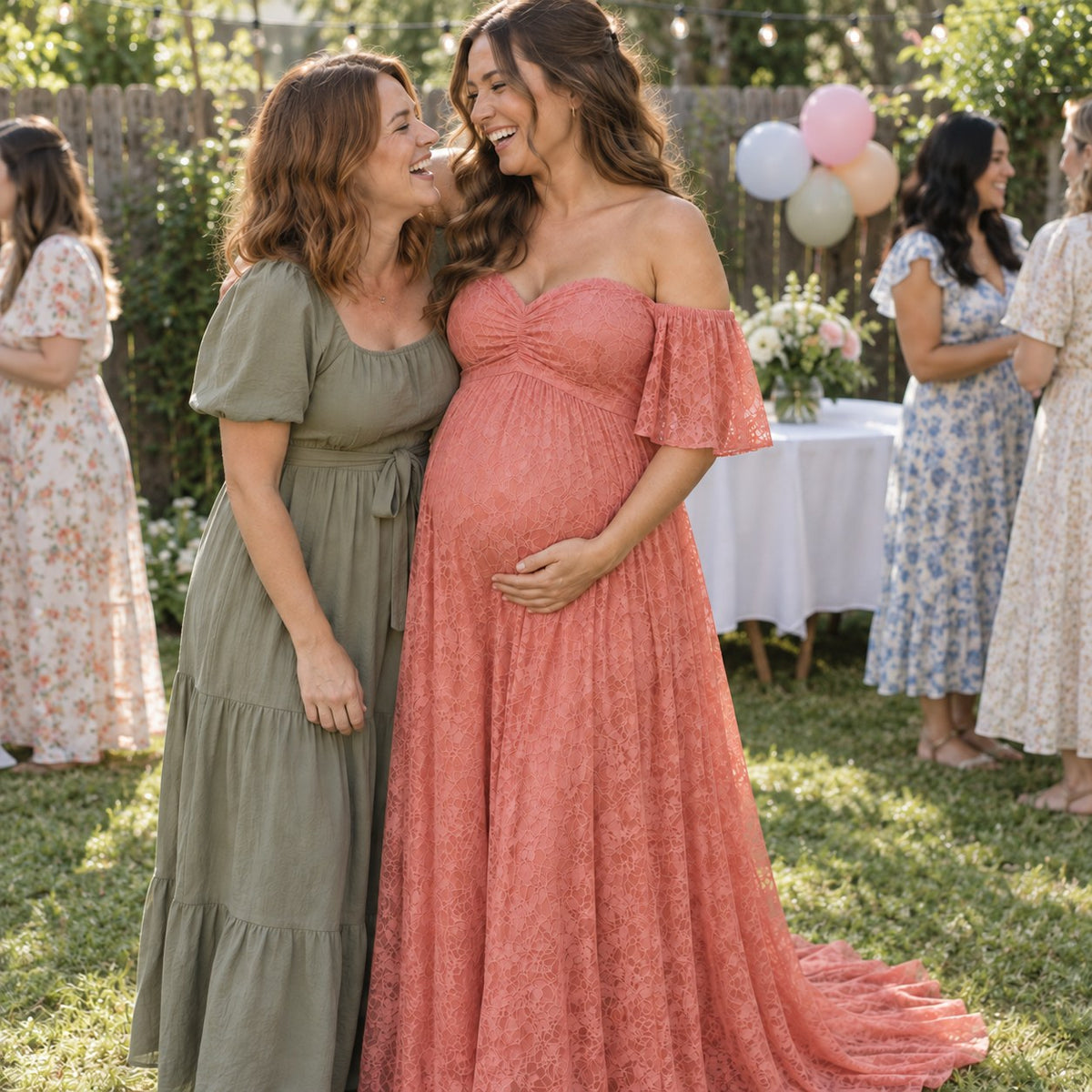Mom-to-be in a coral pink lace dress hugging her best friend at a backyard baby shower
