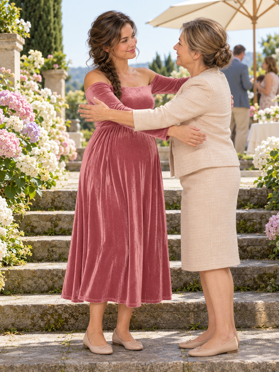 Colette Dusty Rose maternity dress — embraced by an older woman on garden steps with hydrangeas